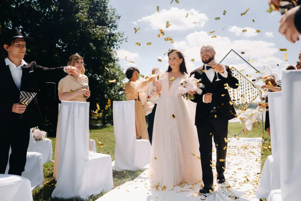A happy wedding couple with glasses of wine passes along the guests
