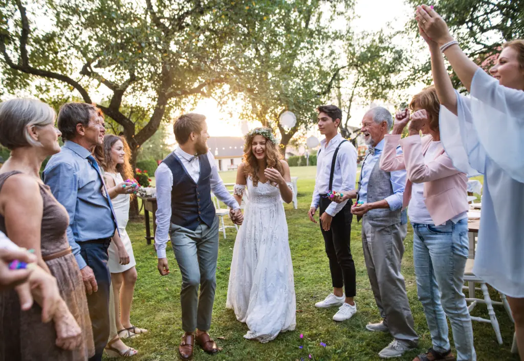 Bride, Groom And Guests At Wedding Reception Outside In The Backyard