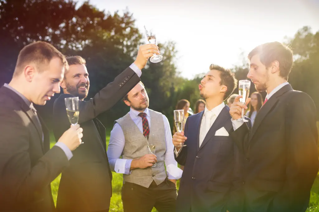 Groom With Four Happy Groomsmen Toasting At The Wedding Reception Outside