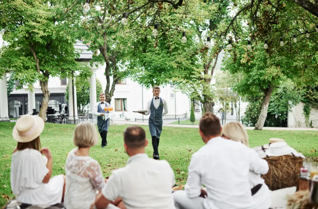 Waiters Serving Drinks to Guests at a Relaxed Outdoor Celebration