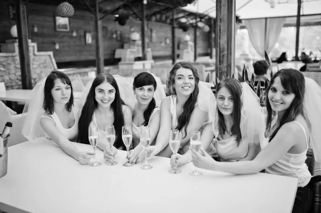 Group of cheerful girls at white shirts sitting at table