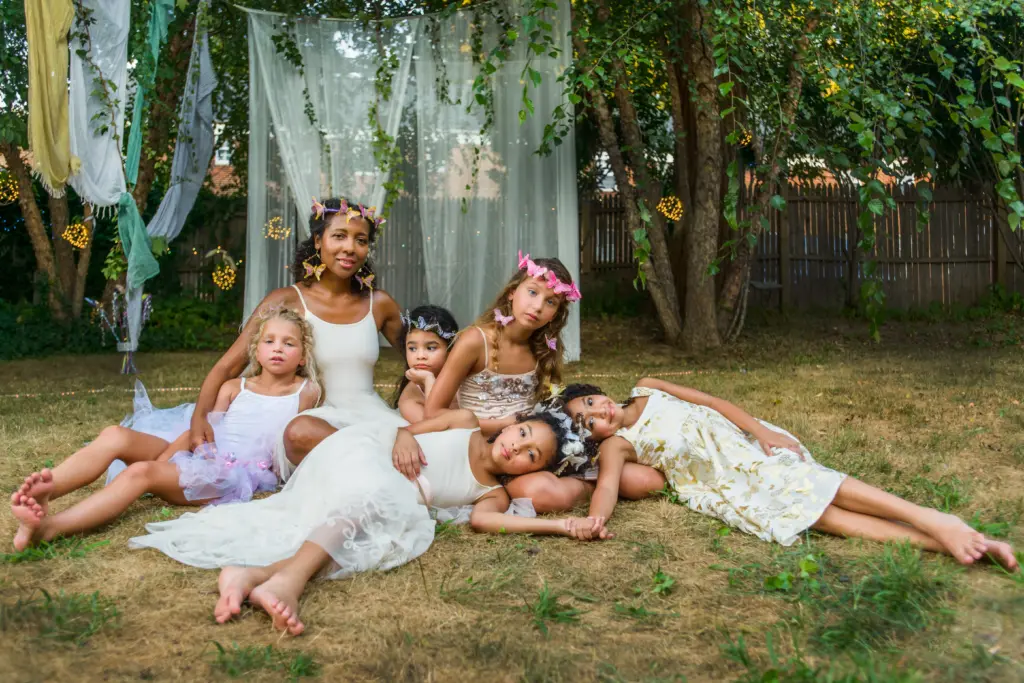 Portrait of mature woman with group of young girls, dressed as fairies, outdoors