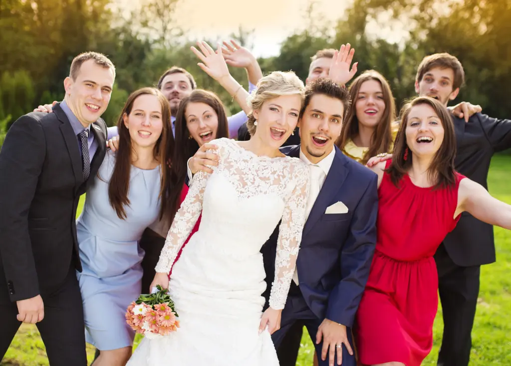 Portrait Of Newlywed Couple Having Fun With Bridesmaids And Groomsmen